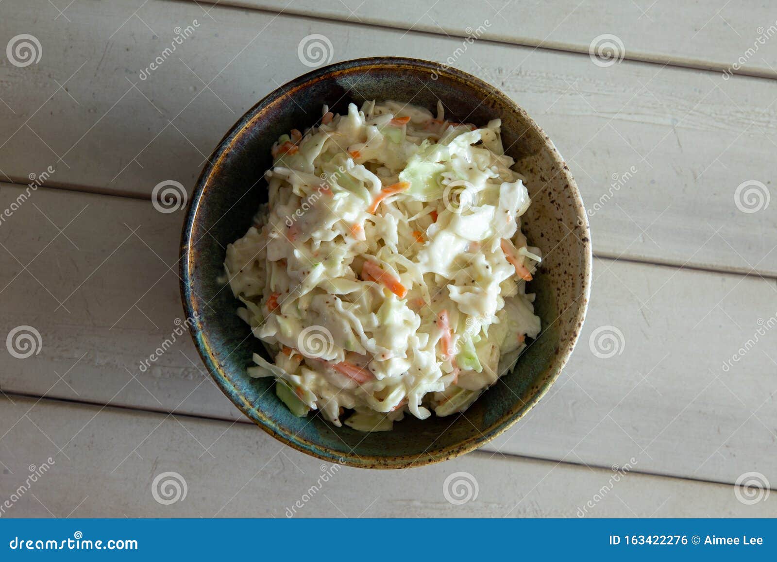 A White Bowl Filled With Coleslaw Sitting On Top Of A Table Next To A Napkin