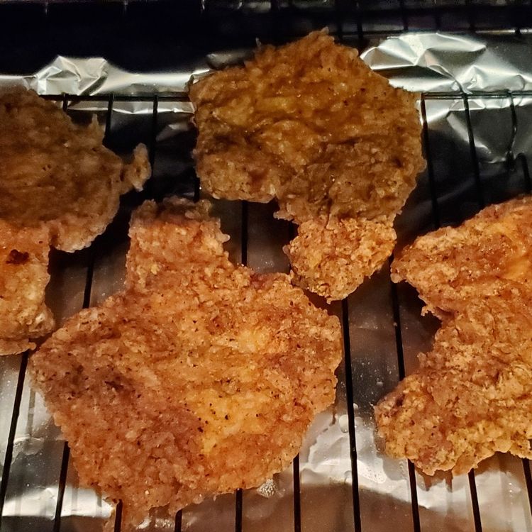 Crispy Fried Pork Chops In A Skillet With Lemon Wedges