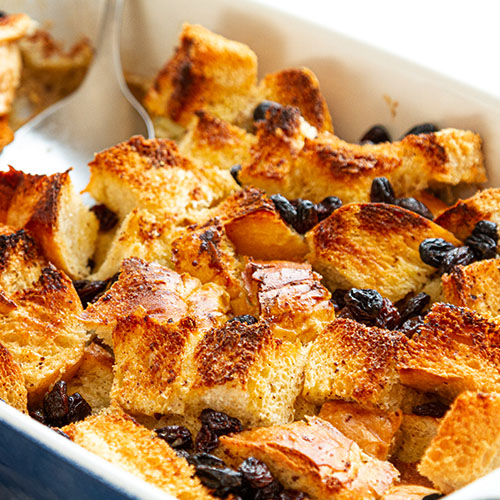 Homemade Bread Pudding Recipe In A Glass Dish On A Checkered Tablecloth